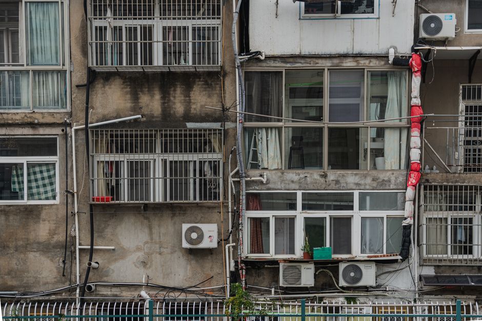 Close view of old apartment building facade with air conditioners and laundry hanging.