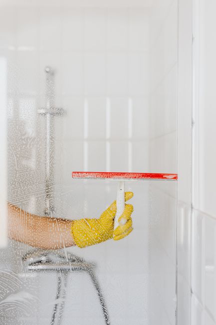 Indoor home kitchen cleaning Cleaner wiping kitchen counter and cabinet surfaces in a bright residential home interior.