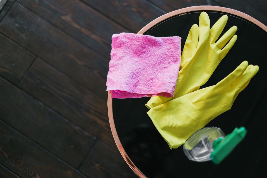 Photo by SHVETS production on Pexels From above of yellow latex gloves placed near rag and spray detergent on table against wooden floor in daytime