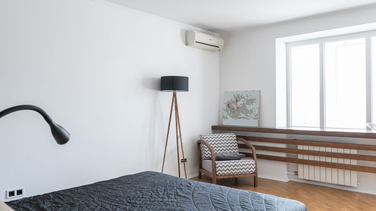 Bright modern bedroom with white walls, large window, and wall-mounted air conditioner. Photo by Max Vakhtbovych on Pexels