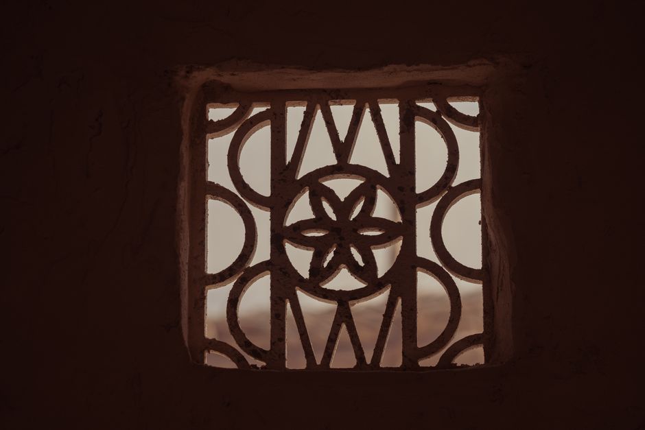 Photo by Denys Gromov on Pexels A detailed view of a decorative window grille with geometric patterns casting shadows.