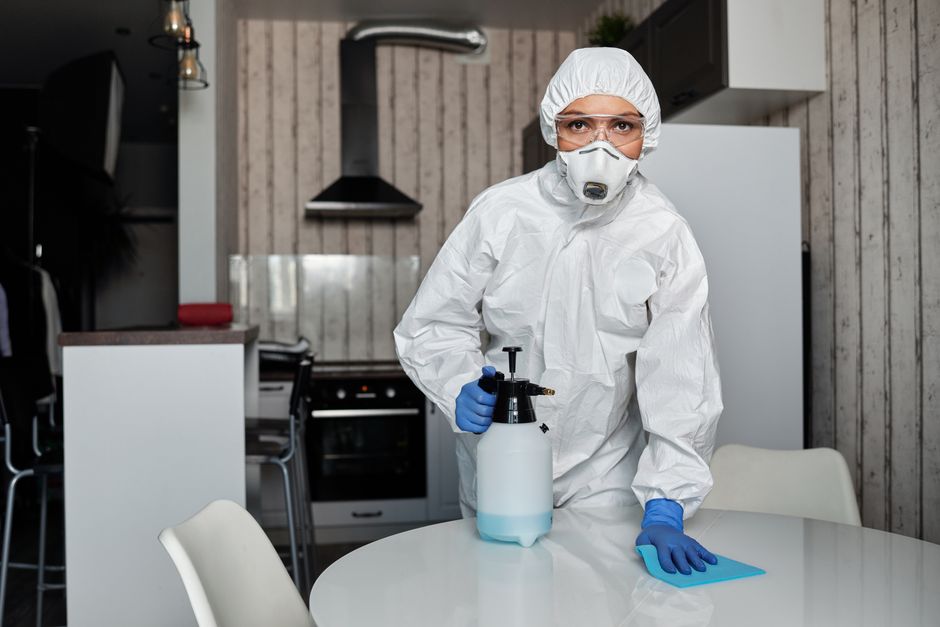 Photo by Matilda Wormwood on Pexels A cleaner in full protective gear disinfects a table indoors, ensuring a sterile environment. - Photo by Matilda Wormwood on Pexels