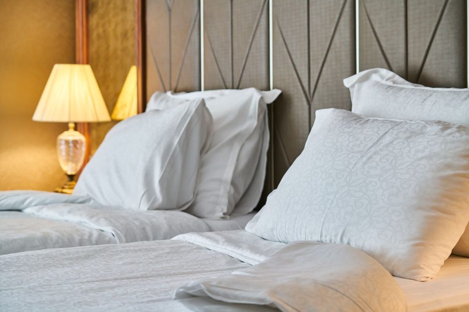 Neatly made bed with white pillows and bedside lamps in a modern bedroom. Photo by Engin Akyurt on Pexels