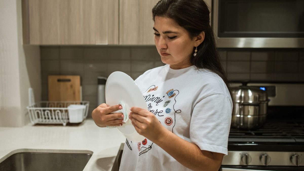 Woman wiping down kitchen surfaces with a cloth in a modern home kitchen. Photo by RDNE Stock project on Pexels