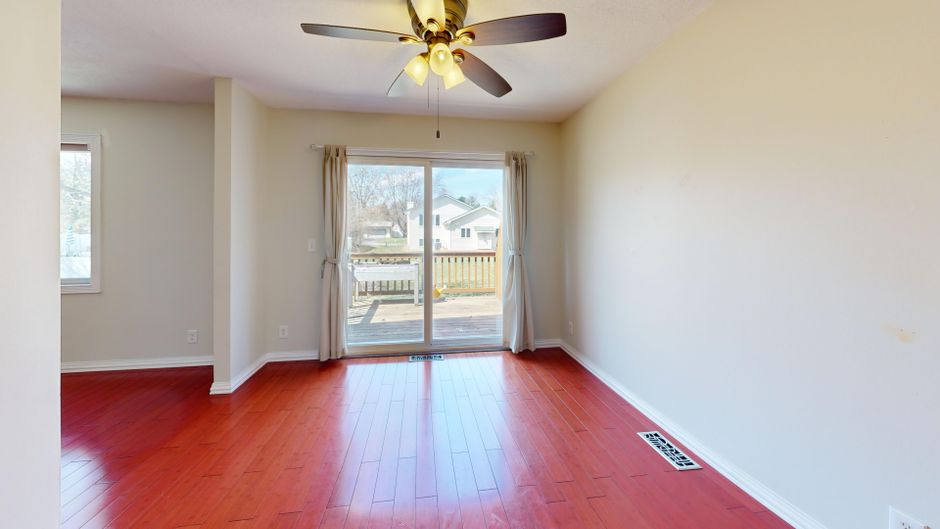Spacious empty room with red wooden flooring, ceiling fan, and patio view. Photo by Peter  Vang on Pexels