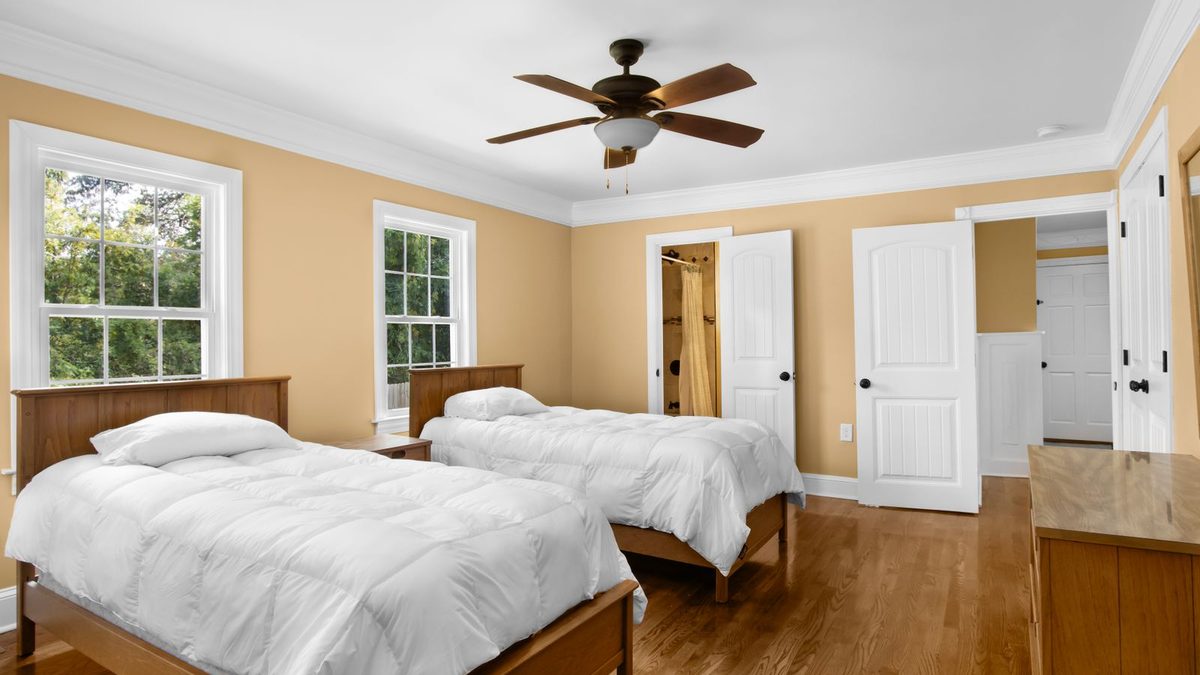Bright bedroom with a ceiling fan above the bed and wooden floor. Photo by Arshad Khan on Pexels