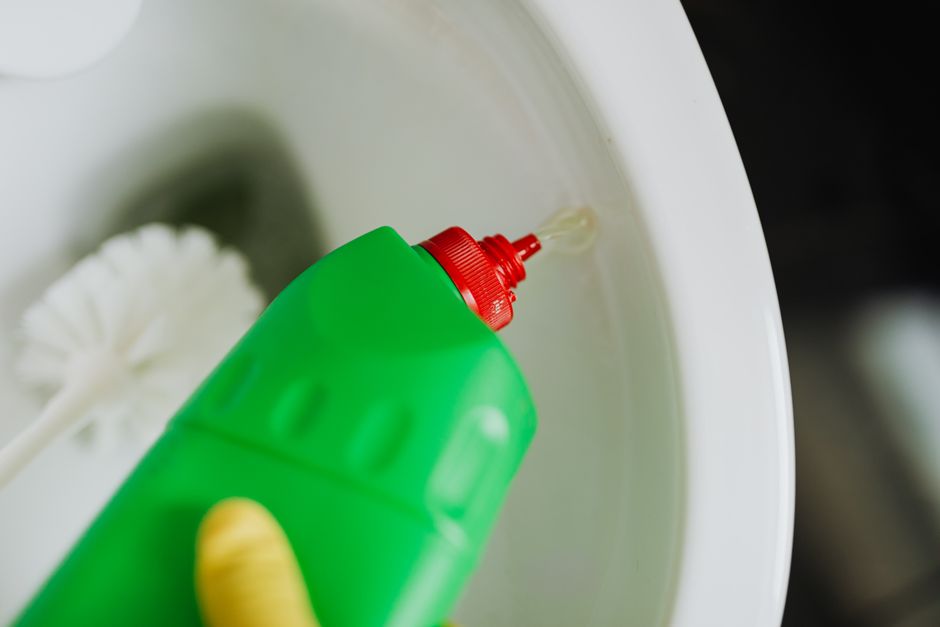 Photo by https://kaboompics.com/ on Pexels Top view of crop faceless person in yellow rubber gloves cleaning toilet with brush and pouring liquid disinfecting cleaner in toilet bowl