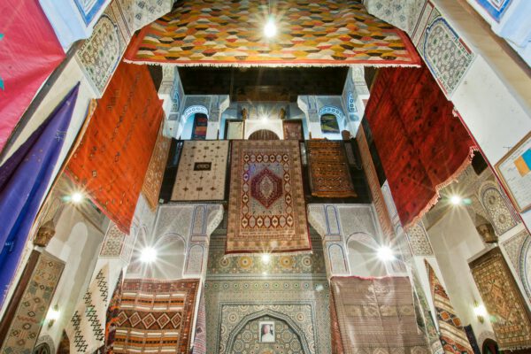 A captivating display of vibrant Moroccan rugs hanging in the historic Medina of Fès, Morocco.