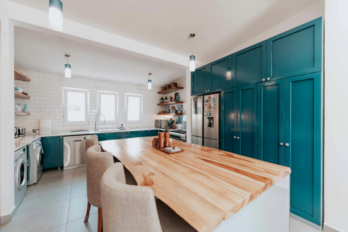 Spacious kitchen featuring teal cabinets, large wooden island, and modern appliances.