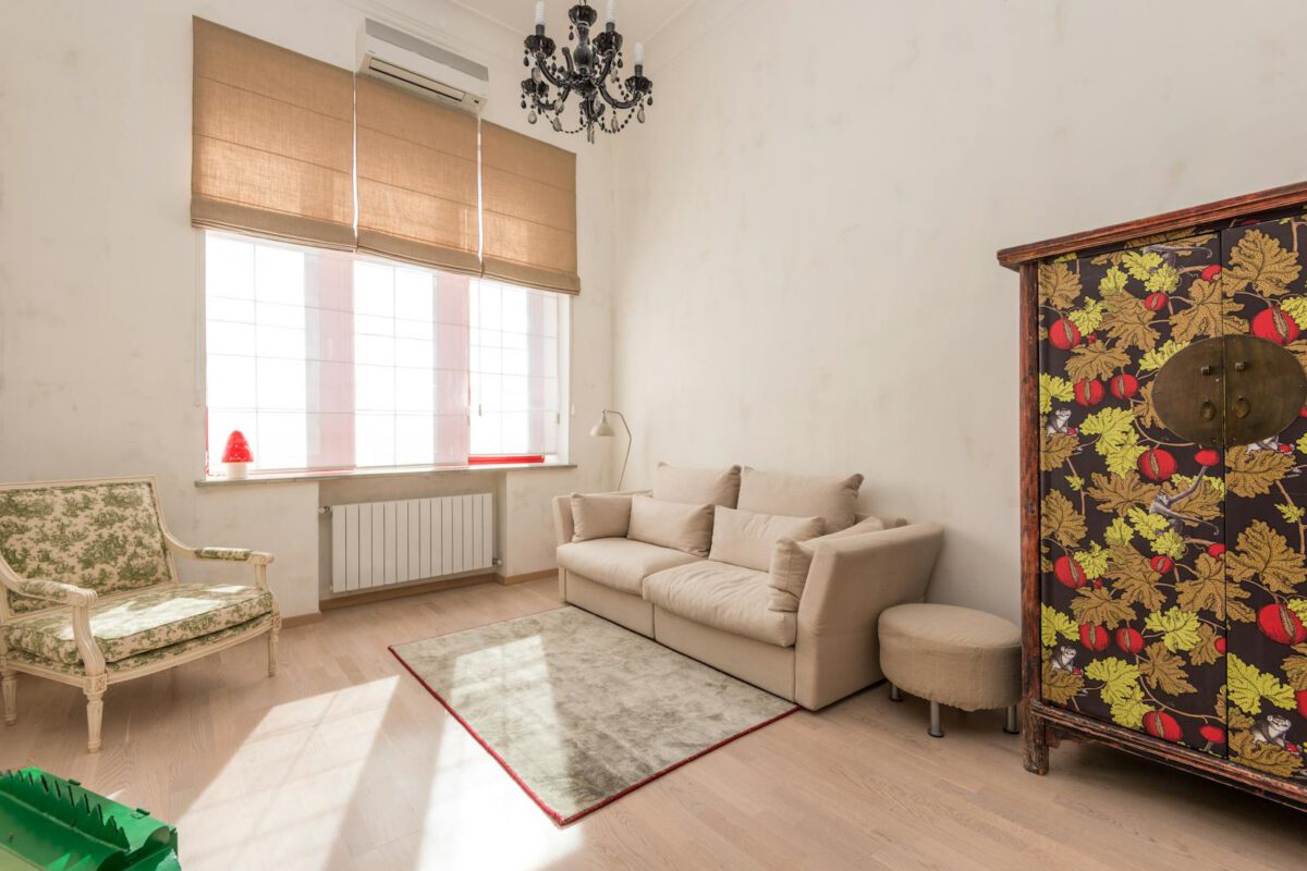 Inviting living room featuring a vintage chair and floral cabinet with abundant natural light.