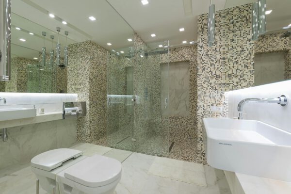 A sleek and spacious modern bathroom featuring elegant mosaic tiles and a glass shower.