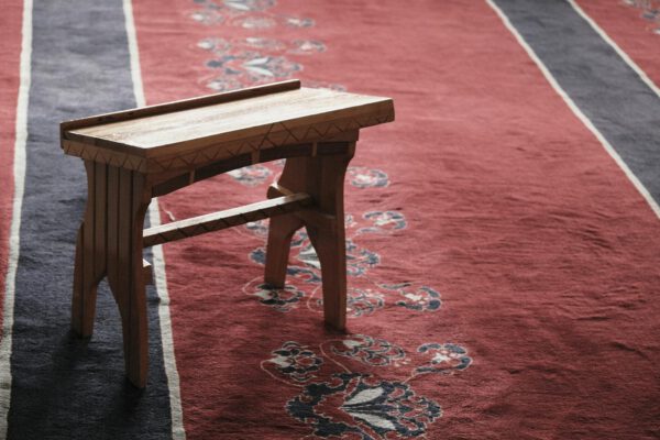 A wooden bench on a vibrant red and blue carpet with intricate patterns.