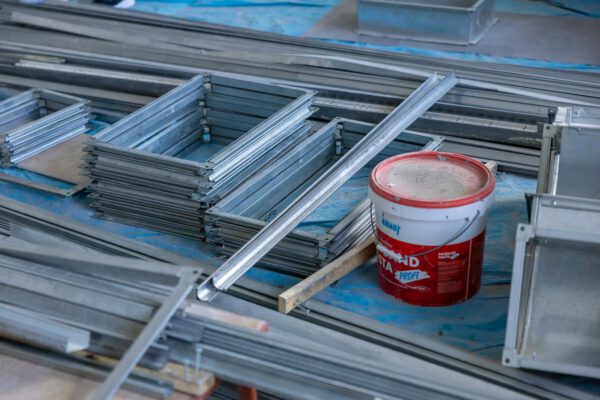 Stacks of metal frames and a paint bucket inside a construction site emphasizing building materials.