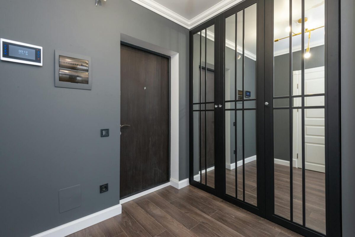 Interior of corridor of modern apartment with wooden doors and parquet floor and mirrored wardrobe