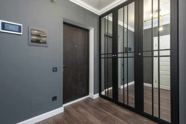 Interior of corridor of modern apartment with wooden doors and parquet floor and mirrored wardrobe