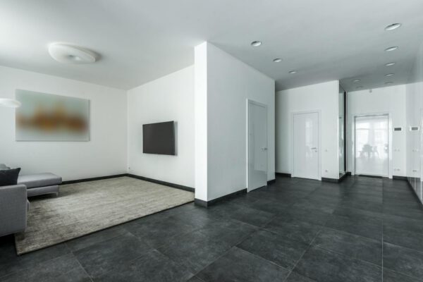 Spacious modern apartment with minimalist design, featuring black floor tiles and white walls.