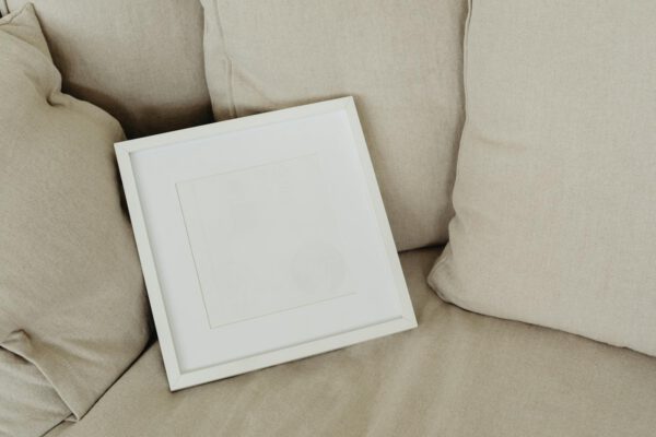 Simple and cozy living room setup featuring a blank wooden frame on a beige sofa.