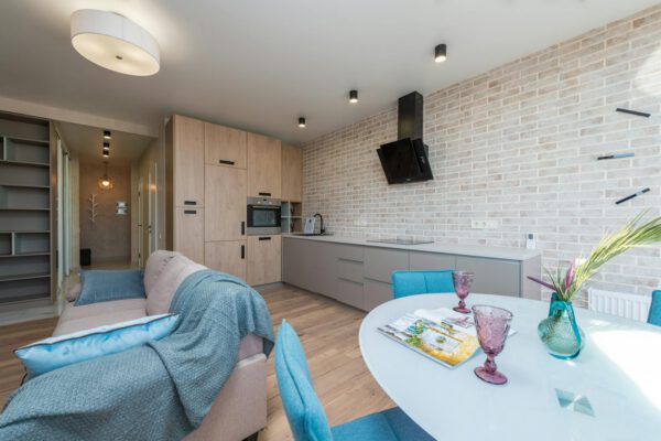 Trendy interior design and decor of comfortable light studio with kitchen furniture and dining table near lounge area in daylight