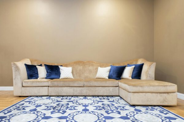 Spacious beige sofa adorned with blue and white throw pillows, set against a neutral wall in a stylish living room.