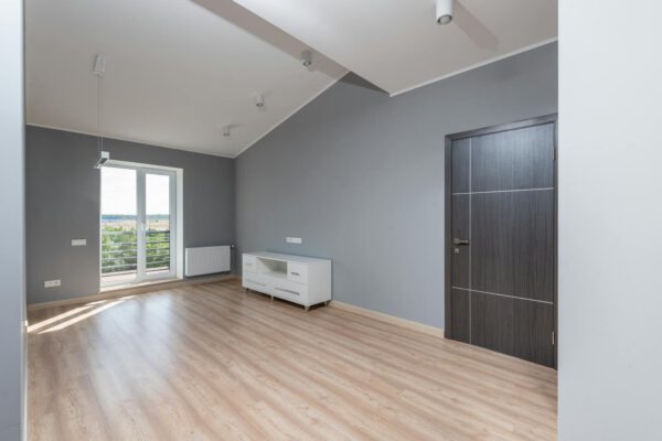 Bright and empty modern room with hardwood floors and large window view.