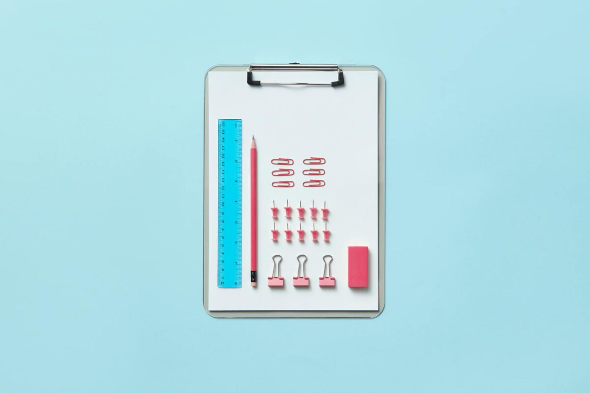 Neatly arranged office supplies on clipboard creating an organized flat lay.