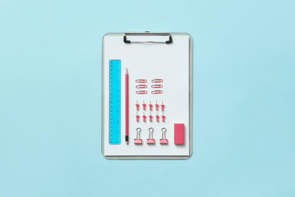 Neatly arranged office supplies on clipboard creating an organized flat lay.