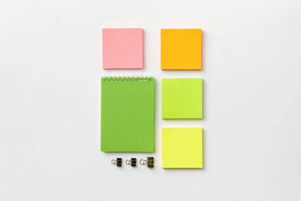 Top view of colorful stationery items including notepad and sticky notes on a white surface.