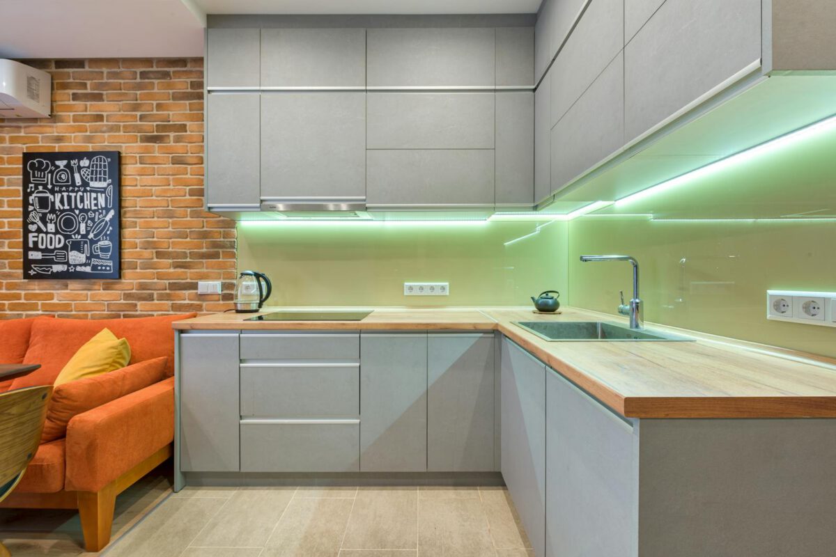 Sleek kitchen with gray cabinets, brick wall, and stylish lighting for a cozy atmosphere.