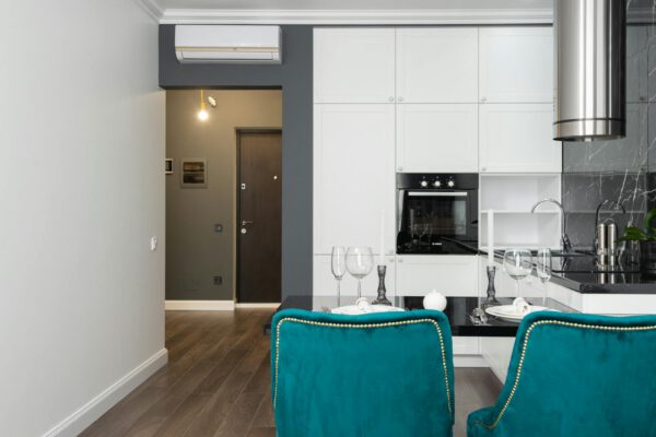 Sleek minimalist kitchen featuring white cabinets and teal accents with a touch of elegance.