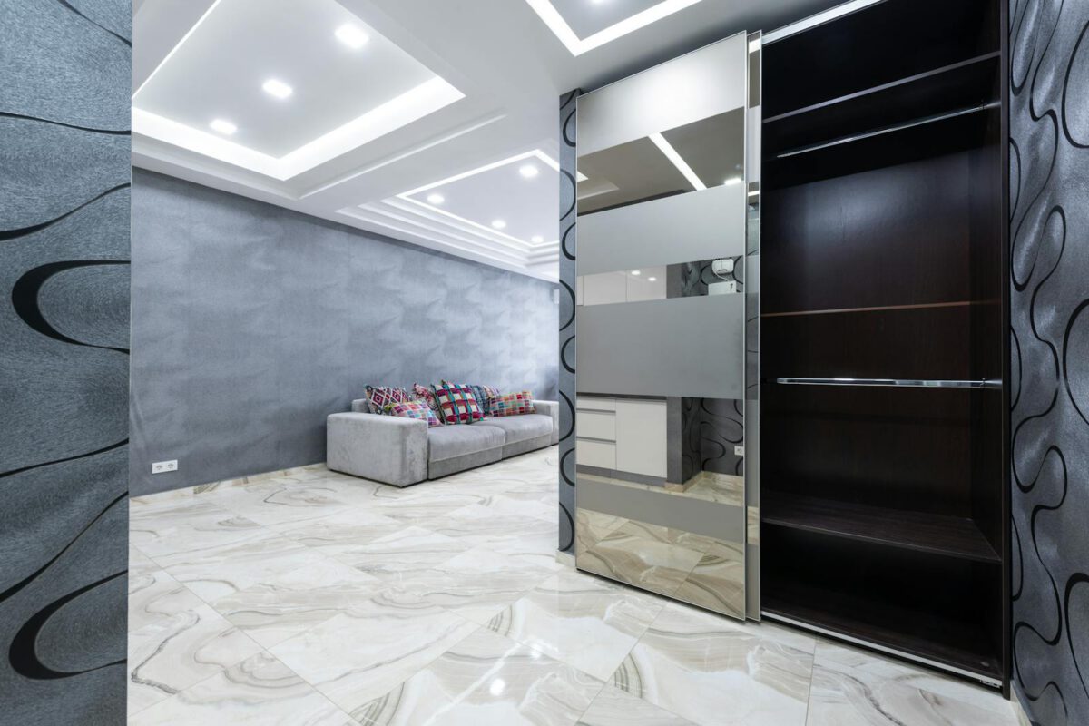 Interior of stylish spacious apartment with opened empty wardrobe and glass doors and gray walls in daytime