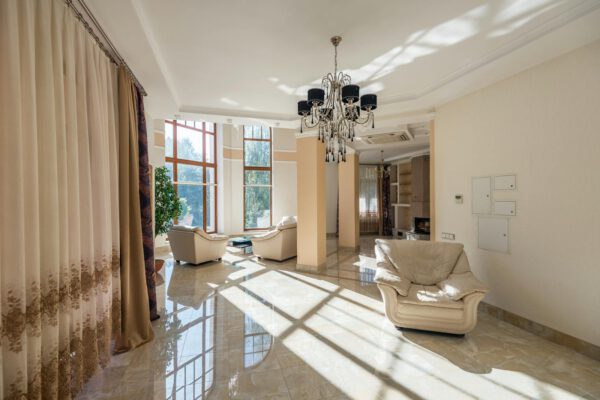 Luxurious living room featuring modern decor, large glass windows, and elegant chandelier.