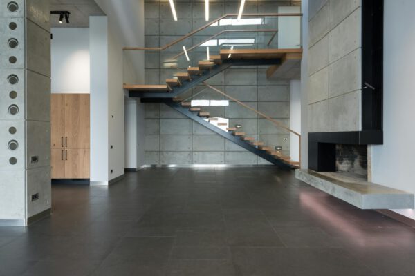 Interior of spacious tiled apartment with staircase with wooden steps leading to second floor