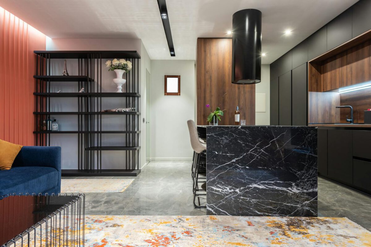 Contemporary living room and kitchen interior with tables and sofa against shelves with flowers and statuettes at home