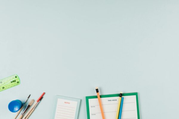 Artistic arrangement of school supplies including pencils, ruler, and notepad with ample copy space.