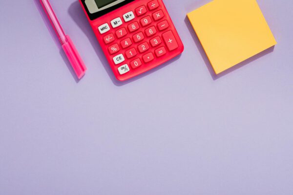 Colorful office essentials like a calculator and sticky notes on a pastel purple background, ideal for productivity themes.