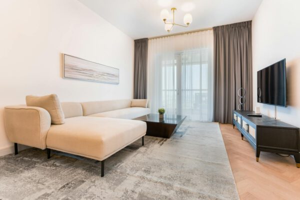 Minimalist living room featuring a beige sofa, coffee table, and TV setup.