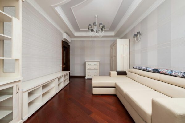 Spacious living room with modern decor, featuring a beige sectional sofa and elegant chandelier.