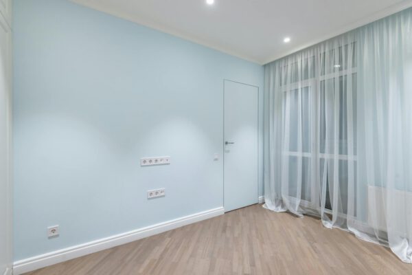 Interior of spacious empty room with beige laminate and white walls under luminous lamps