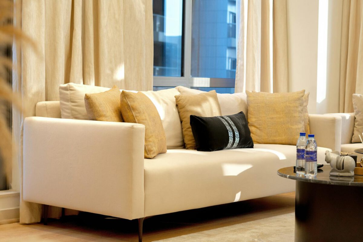Chic living room with a beige sofa, cushions, and a glass table offering a modern aesthetic.