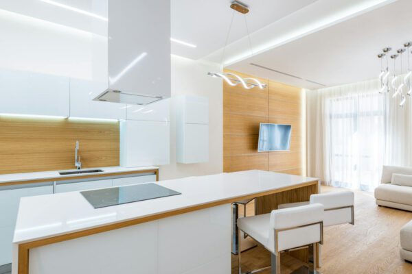 Stylish empty kitchen with expensive white furniture in spacious modern apartment in daylight