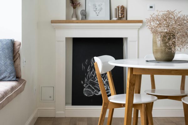 Interior details of light cozy living room with round dining table with chairs and soft cushions on windowsill in daytime