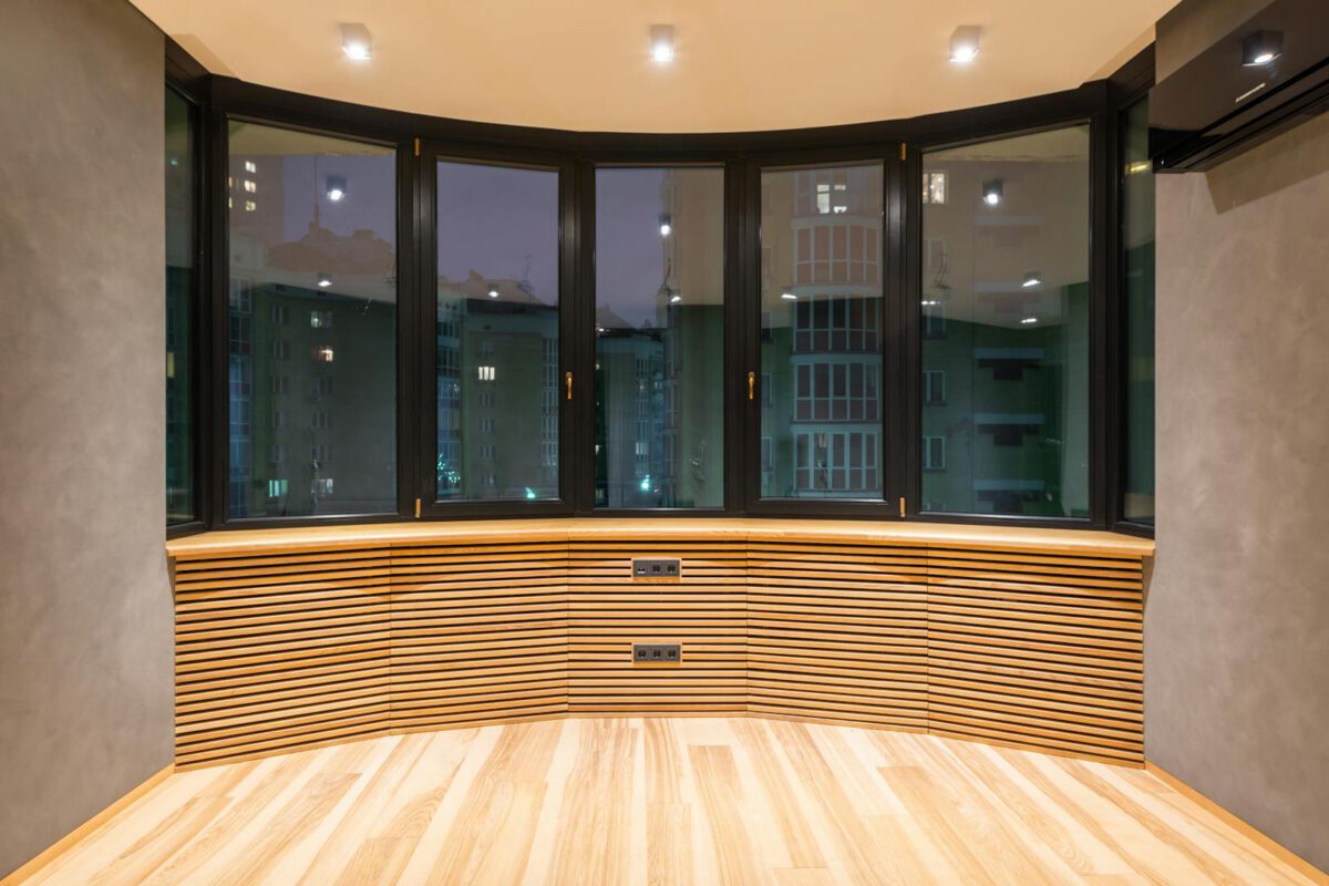 Contemporary empty room with windows and parquet under bright lamps against air conditioning in urban house