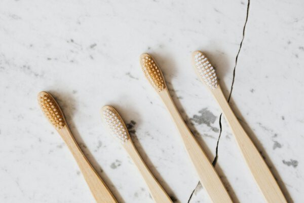 Flat lay of four bamboo toothbrushes on marble surface emphasizing eco-friendly dental hygiene.