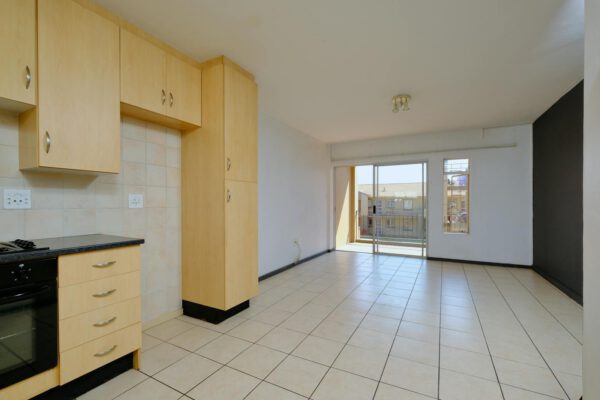 Empty modern apartment with light wood cabinets and balcony access.