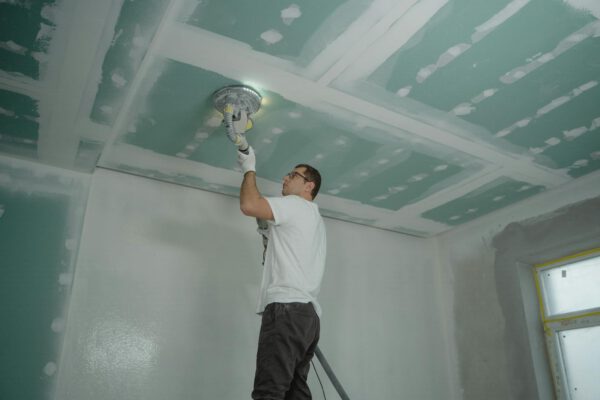 Worker polishing a ceiling indoors during home renovation