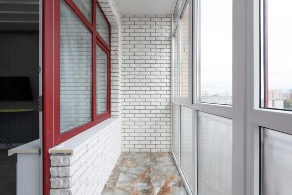 Interior of light balcony with marble floor and panoramic windows in apartment in daytime