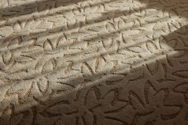 Close-up of a textured beige carpet with floral pattern