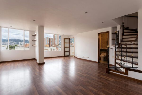 Bright empty living room with wooden floors and large windows