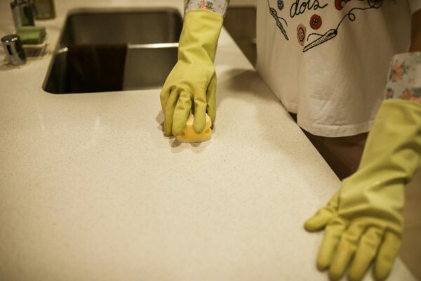 Person in yellow gloves deep cleaning a kitchen counter