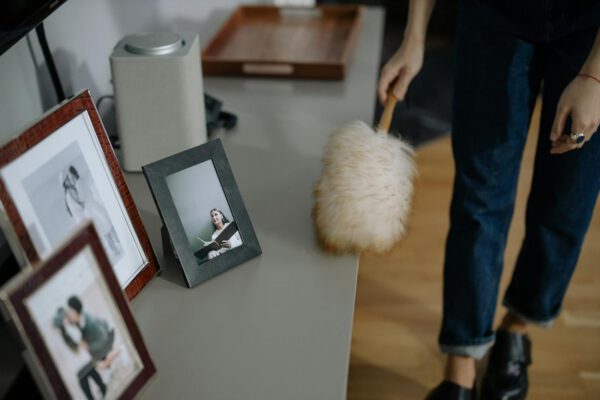 Person using a feather duster to remove dust from picture frames